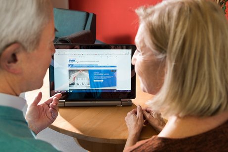 Ein älteres Paar am Computer, auf dem Bildschirm sieht man die Facebook-Seite des VdK Deutschland