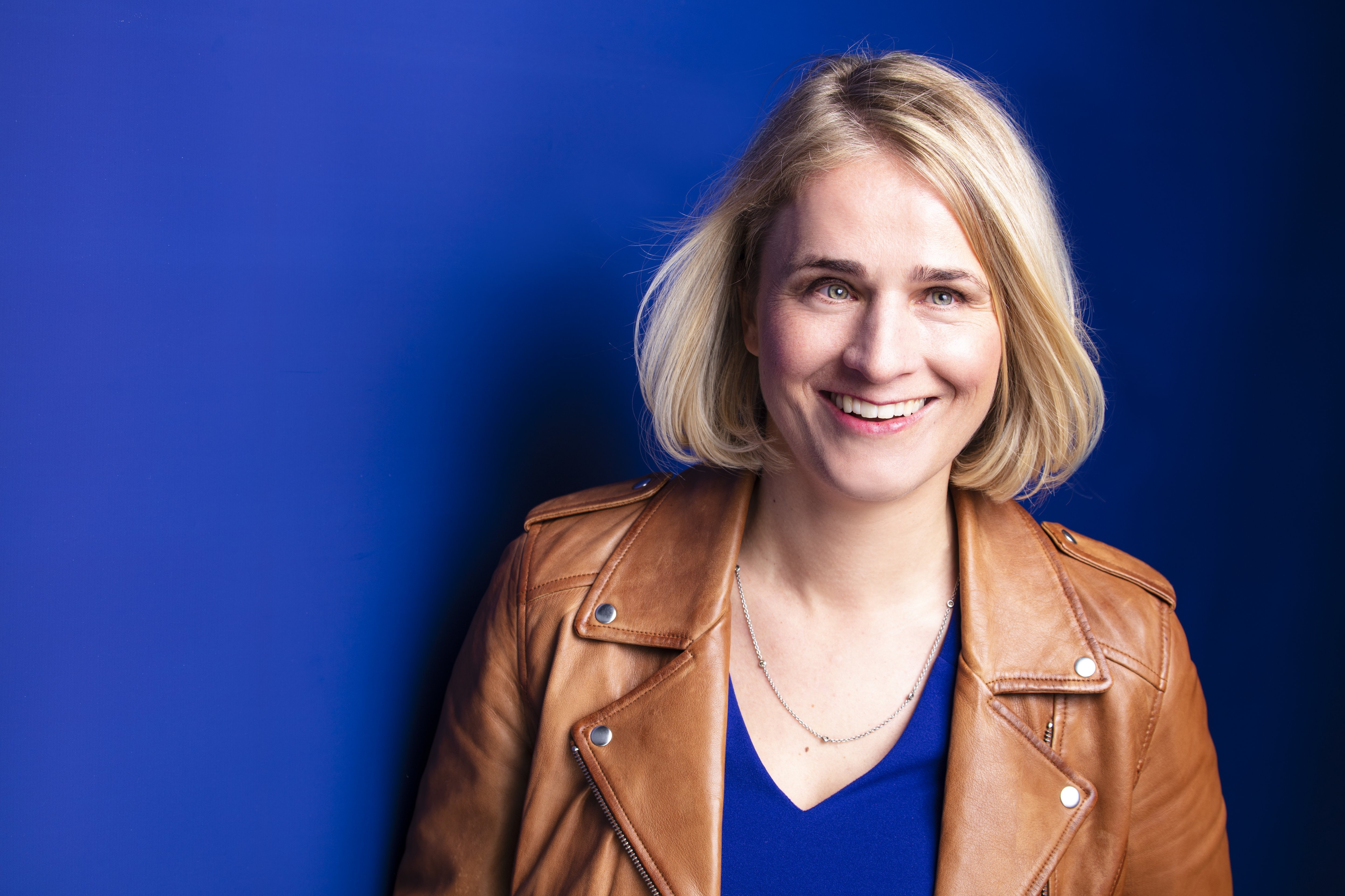 Verena Bentele Das Portraitfoto zeigt VdK-Präsidentin Verena Bentele lachend vor einem blauen Hintergrund.