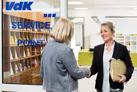 VdK-Beratungsstelle Eine VdK-Mitarbeiterin begrüßt eine Frau an der Tür einer VdK-Beratungsstelle. Sie hat eine Aktenmappe unter dem Arm.