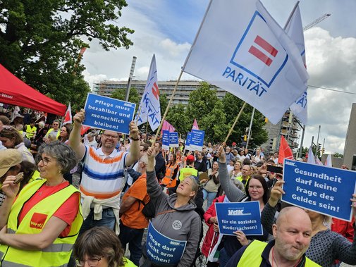 Menschen halten in der Menge VdK-Plakate hoch