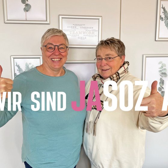 Birgit Becker und Jutta Da Corte mit Daumen hoch und dem Schriftzug "Wir sind jasozial!"