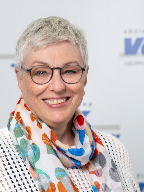 Birgit Becker l&auml;chelnd vor dem VdK-Logo