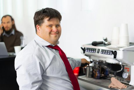 Ein Mann mit Down-Syndrom bei der Arbeit an einer Kaffeemaschine