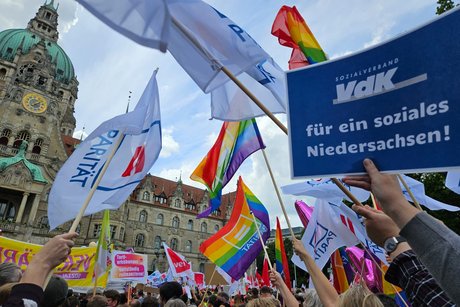 Menschen halten Fahnen und Schilder während der Kundgebung am 10. Juni hoch