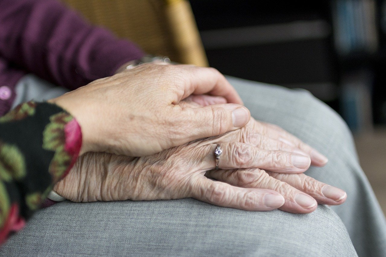 Die Hand einer Frau auf den Händen einer älteren Frau