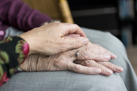 Die Hand einer Frau auf den Händen einer älteren Frau