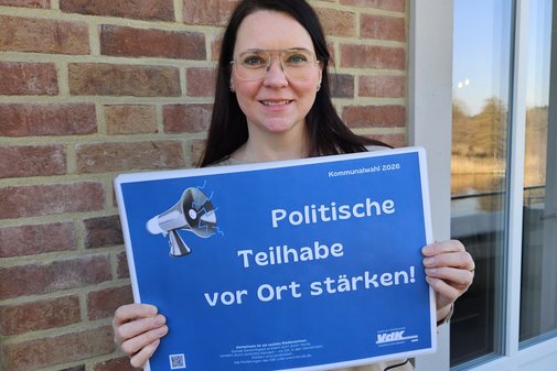 Andrea Nacke h&auml;lt l&auml;chelnd ein Plakat mit Forderungen hoch