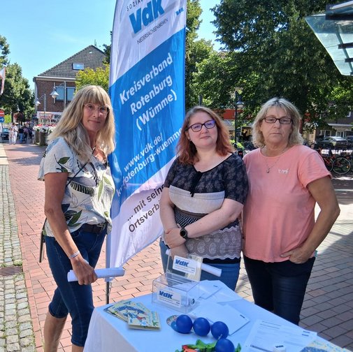 Drei Ehrenamtliche am blau-weißen Infostand