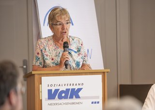 Gunda Menkens bei einer Rede am Pult mit VdK-Logo 
