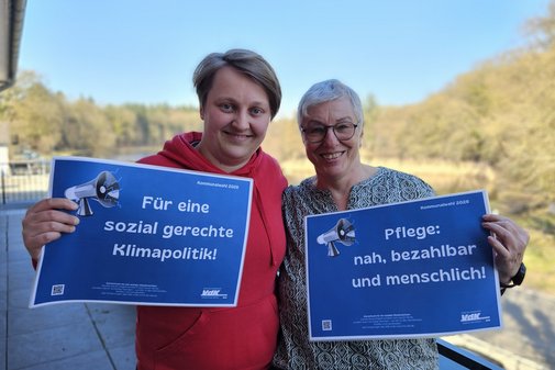 Die beiden Frauen halten l&auml;chelnd zwei Schilder mit den Forderungen hoch