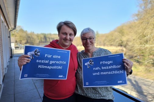 Die beiden Frauen halten l&auml;chelnd zwei Schilder mit den Forderungen hoch