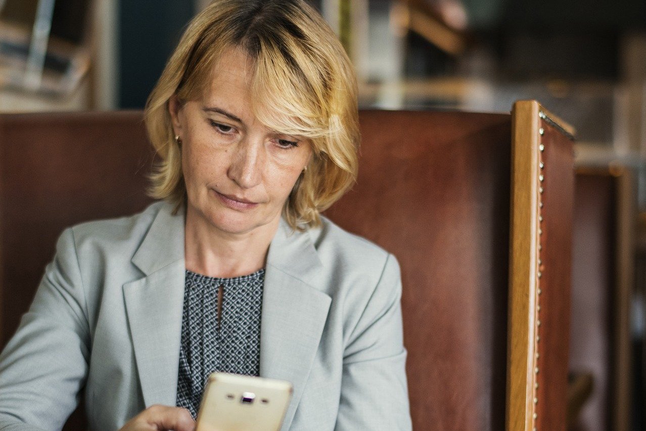 Eine Frau sitzt im Cafe mit einem Smartphone