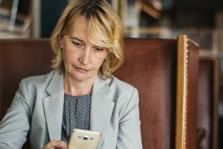 Eine Frau sitzt im Cafe mit einem Smartphone
