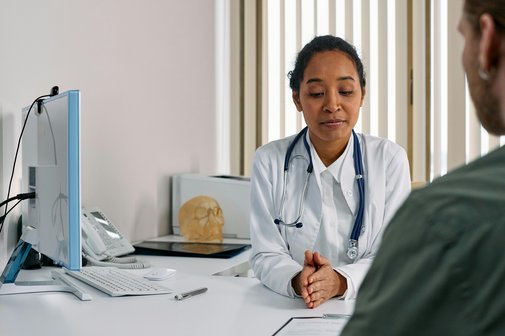 Eine Ärztin am Schreibtisch bespricht etwas mit einem Patienten