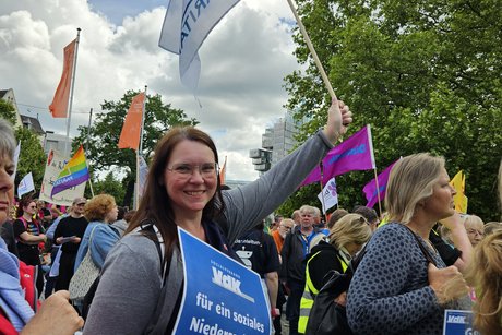 Andrea Nacke von der sozialpolitischen Abteilung im VdK hält Plakat und Fahne hoch
