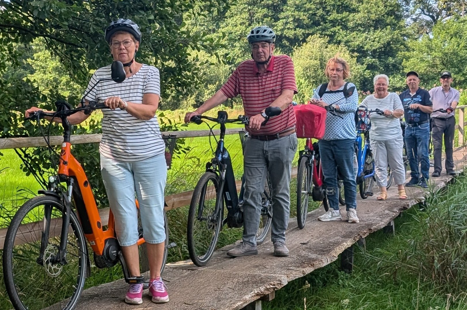 Die Fahrradfahrer auf einer schmalen Br&uuml;cke im Gr&uuml;nen