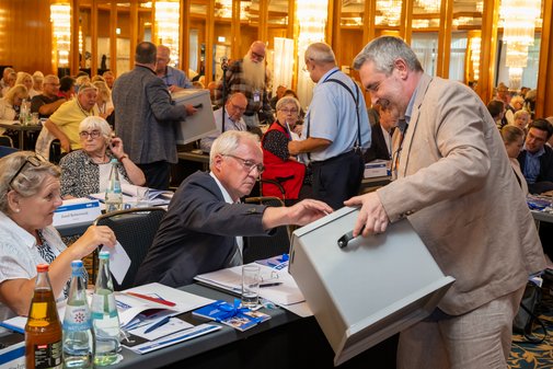 Ein Kollege mit der Stimmbox beim Einsammeln der Stimmzettel