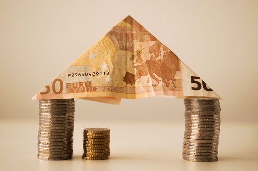 Ein 50-Euro-Schein und M&uuml;nzen bilden ein Haus