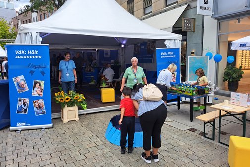 Eine Mutter mit Kind spielt Entenangeln, eine Frau und ein Junge spielen Kicker