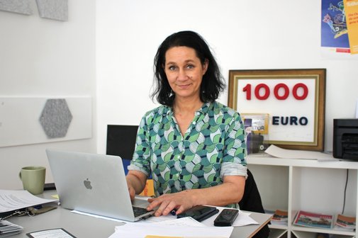 Frau Weiß sitzt am Laptop am Schreibtisch