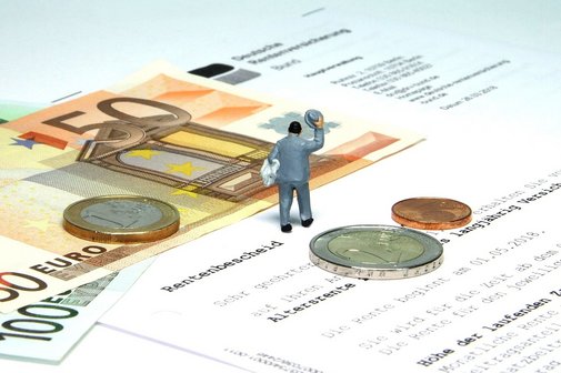 Ein Rentenbescheid, dazu Geldscheine und M&uuml;nzen und eine m&auml;nnliche Figur im Anzug