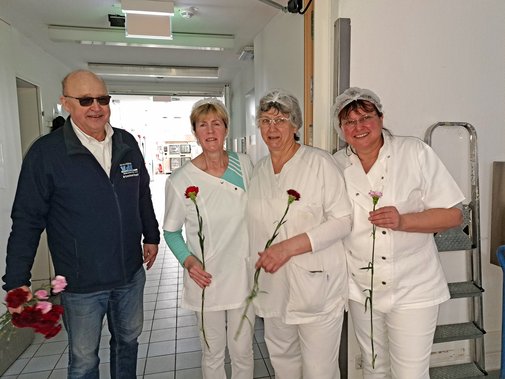 Ein Ehrenamtlicher verteilt Rosen an Mitarbeiterinnen