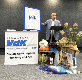 Uwe Wagner mit den Unterschriften auf einem Bilderrahmen mit VdK in der Mitte