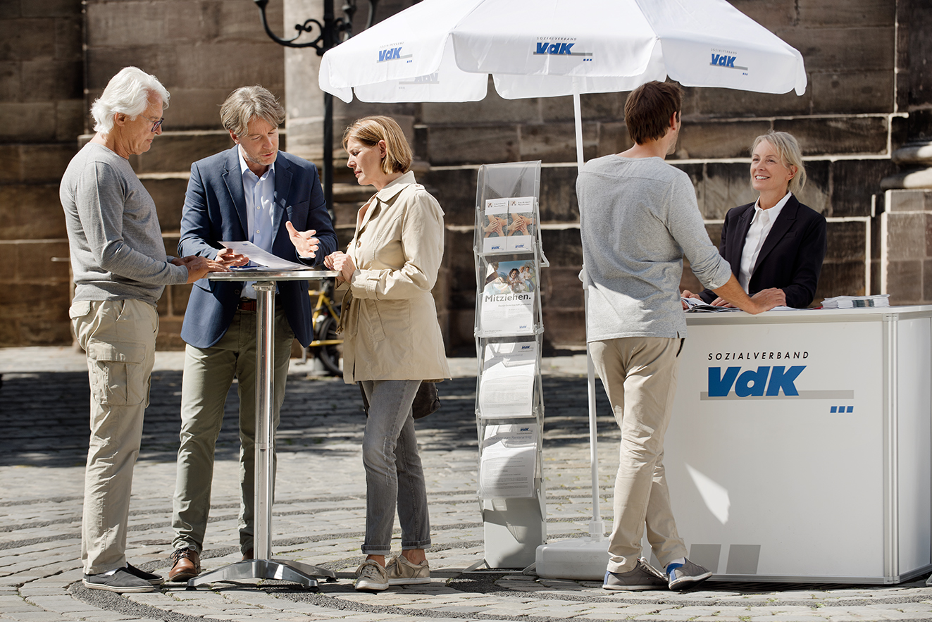 Menschen an einem blau-wei&szlig;en VdK-Infostand