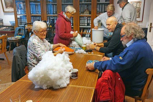 Die Ehrenamtlichen am Tisch mit Stoffen und Wolle