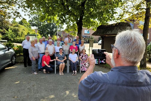 Ein Ehrenamtlicher macht als Übung mit einem Smartphone ein Gruppenfoto