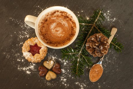 Ein Milchkaffee mit Keksen und einem Tannenzweig