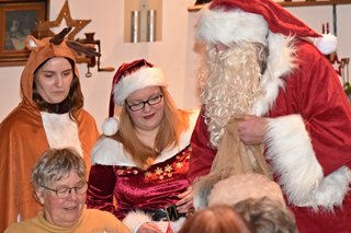 Der Weihnachtsmann und seine Helferinnen überreichen kleine Geschenke.