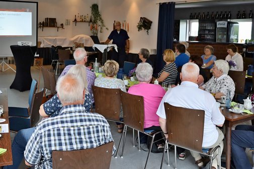Mitglieder des VdK Celle-Altstadt sitzen an Tischen und hören dem Brandmeister Thomas Drösemeyer zu.