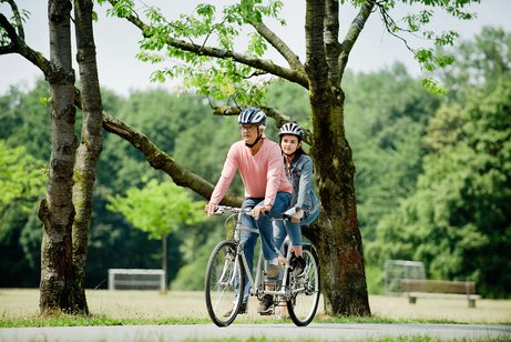 Ein &auml;lterer Mann und eine Teenagerin fahren gemeinsam auf einem Tandem.