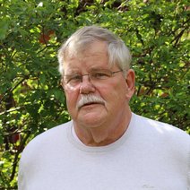 Portraitfoto von Michael Gunkel vor einer gr&uuml;nen Hecke.