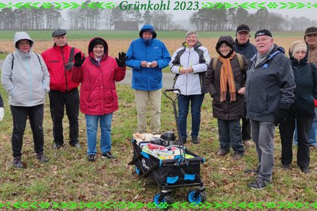 Warm angezogene Grünkohlwandergruppe mit Bollerwagen auf freiem Feld