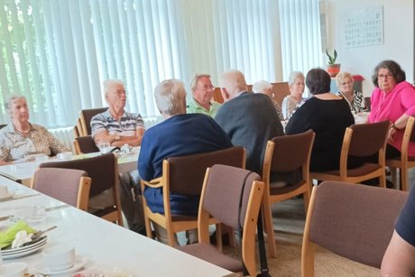 Menschen sitzen an einem Tisch zusammen beim Fr&uuml;hst&uuml;ck