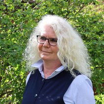 Portraitfoto von Angela Pengel vor einer gr&uuml;nen Hecke.