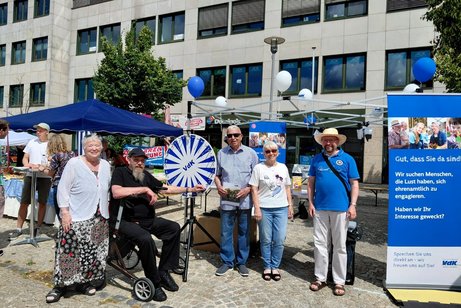 Das Bild zeigt eine Personengruppe an einem Infostand des VdK.