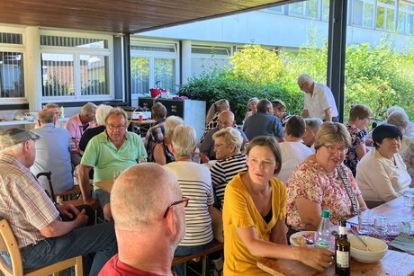 mehrer Personen sitzen an Bierzeltgarnituren zusammen