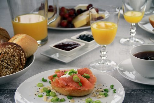 Fr&uuml;hst&uuml;cksgedeck mit Br&ouml;tchen, Kaffee und Orangensaft