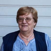 Eine &auml;ltere Frau mit dunklen Haaren, get&ouml;nter Brille, einem hellblauen Shirt mit Weste