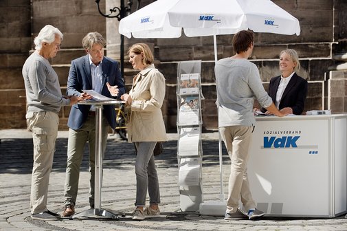 Menschen an einem blau-wei&szlig;en VdK-Infostand