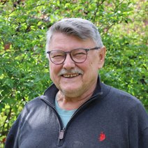 Portraitfoto von Rolf Zimmermann vor einer gr&uuml;nen Hecke.