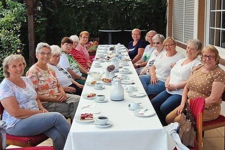 Die lächelnden Frauenvertreterinnen zusammen am langen Tisch mit Kaffee und Kuchen