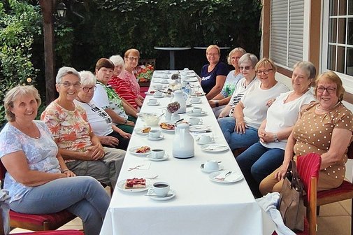 Die lächelnden Frauenvertreterinnen zusammen am langen Tisch mit Kaffee und Kuchen