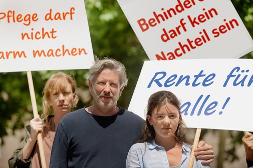 Gruppe von Menschen verschiedenen Geschlechts und Alters, mit und ohne Behinderung, demonstrieren. Auf den Demopappen steht "Pflege darf nicht arm machen", "Behinderung darf kein Nachteil sein" und "Rente f&uuml;r alle"