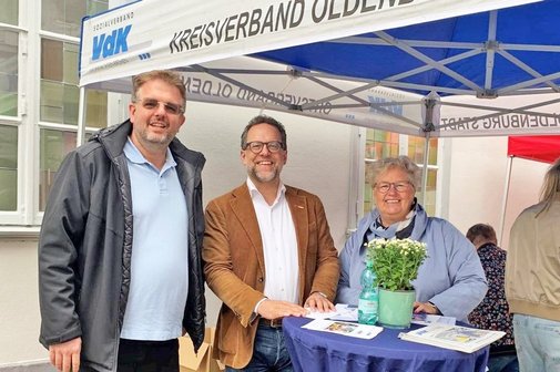 Die drei Personen im blau-weißen Messezelt.