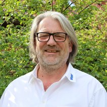 Portraitfoto von Matthias Kr&uuml;ger vor einer gr&uuml;nen Hecke.
