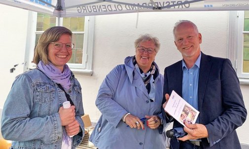 Die drei Personen l&auml;chelnd im Infostand
